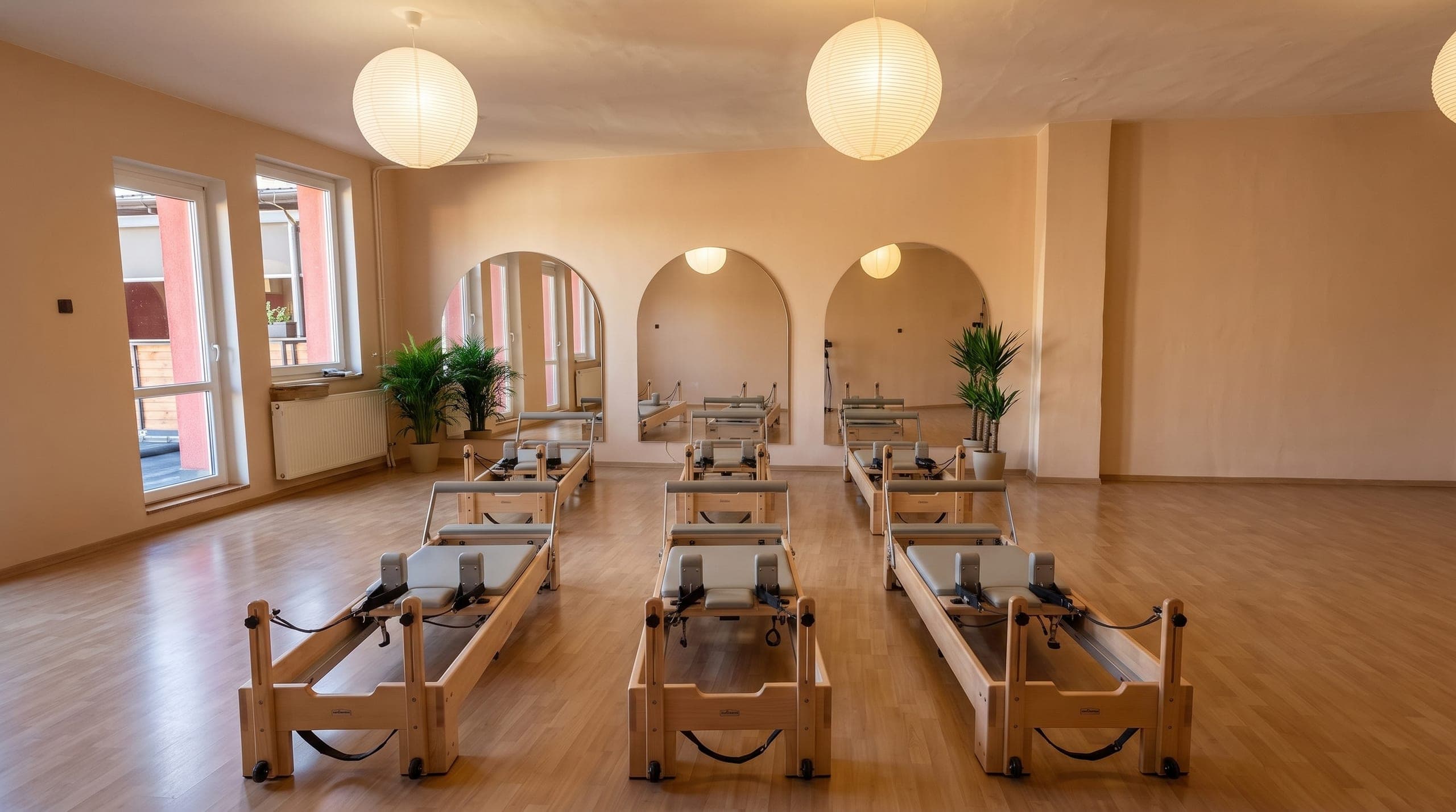 Sál Axis Pilates se šesti reformery, denním světlem a zrcadlovými oblouky